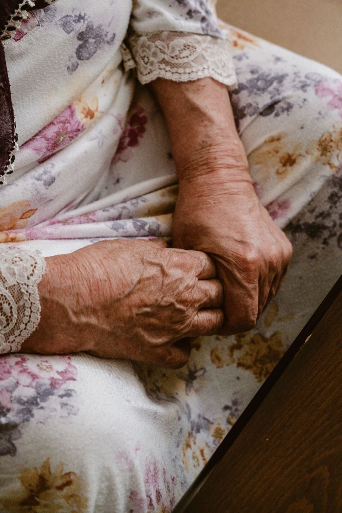 Close-up of an older woman's hands resting gently clasped in her lap