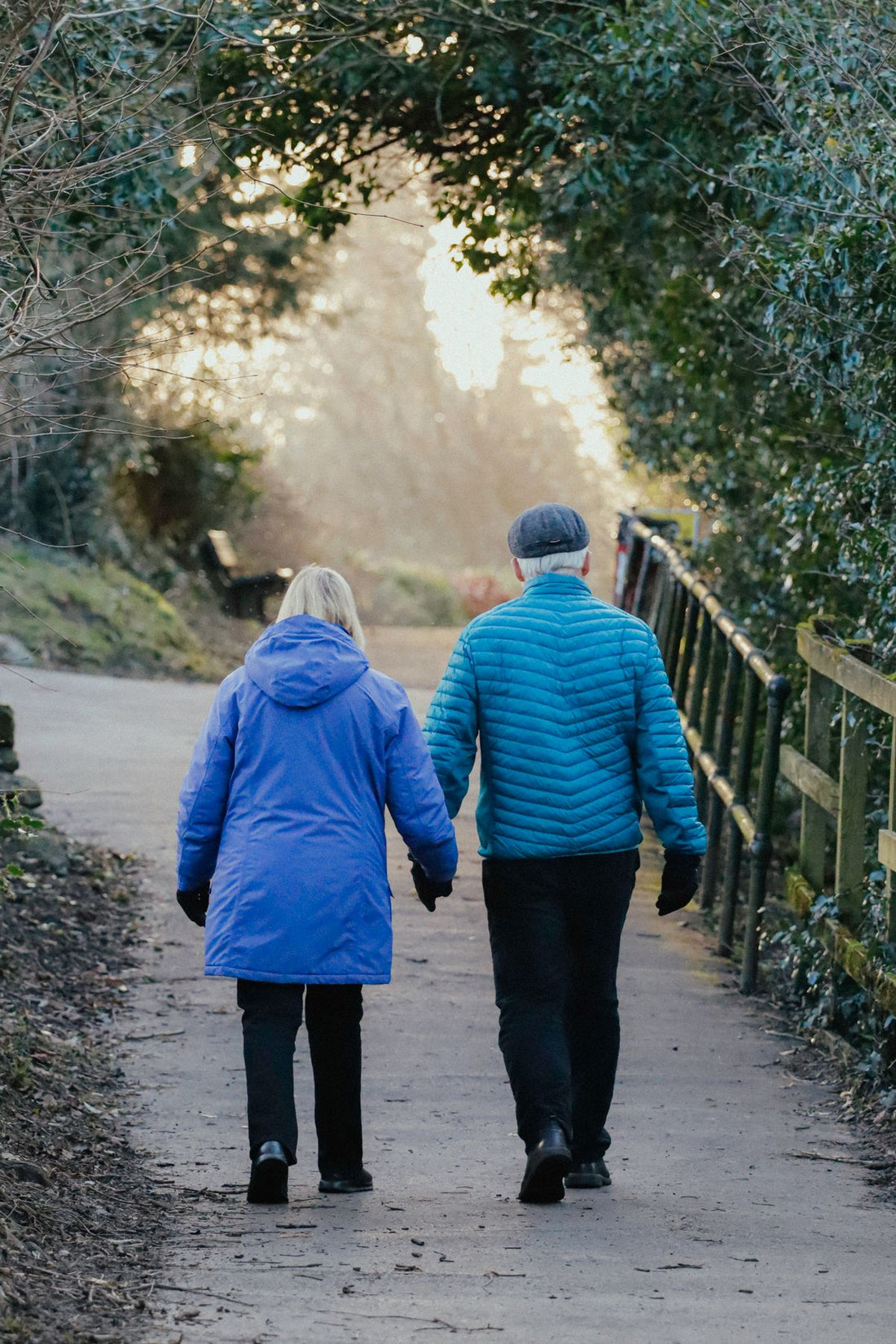 Senior couple walking together on a park pathway at sunset