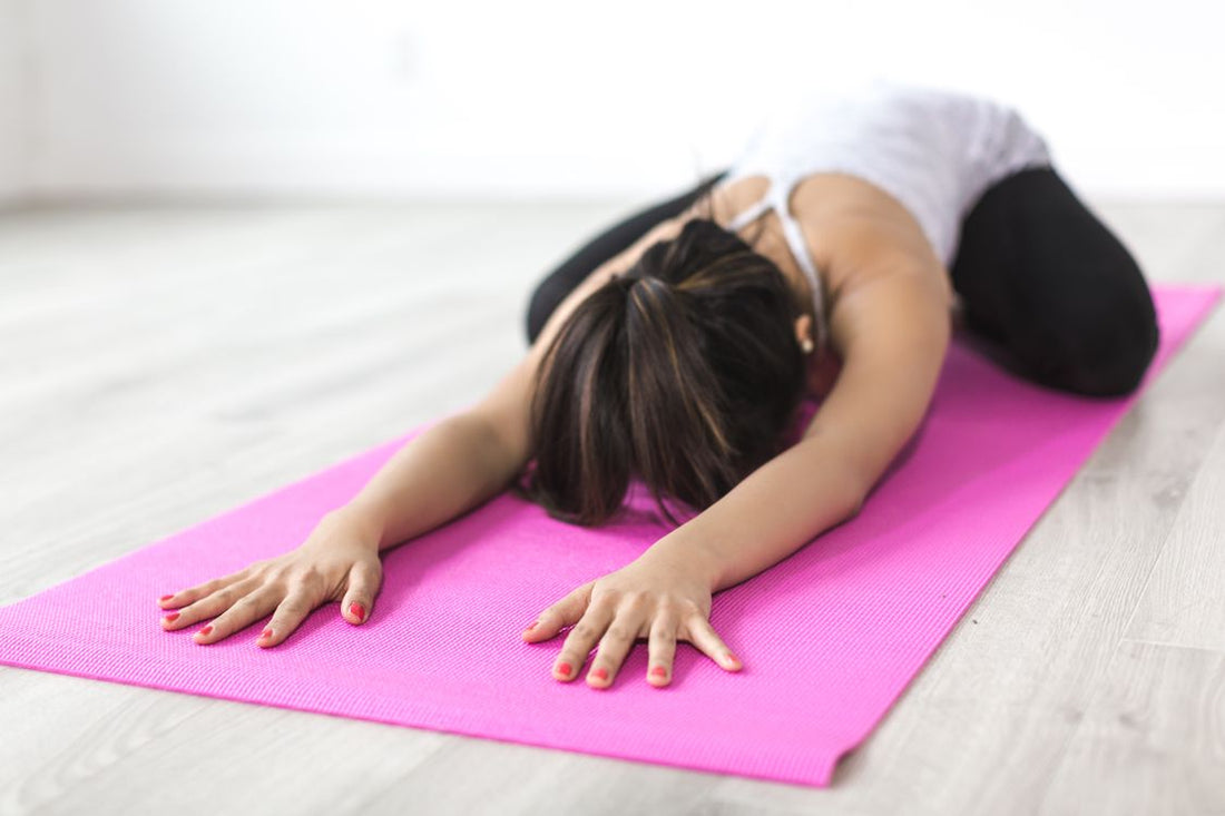 Adult practicing a gentle stretch pose on a mat indoors