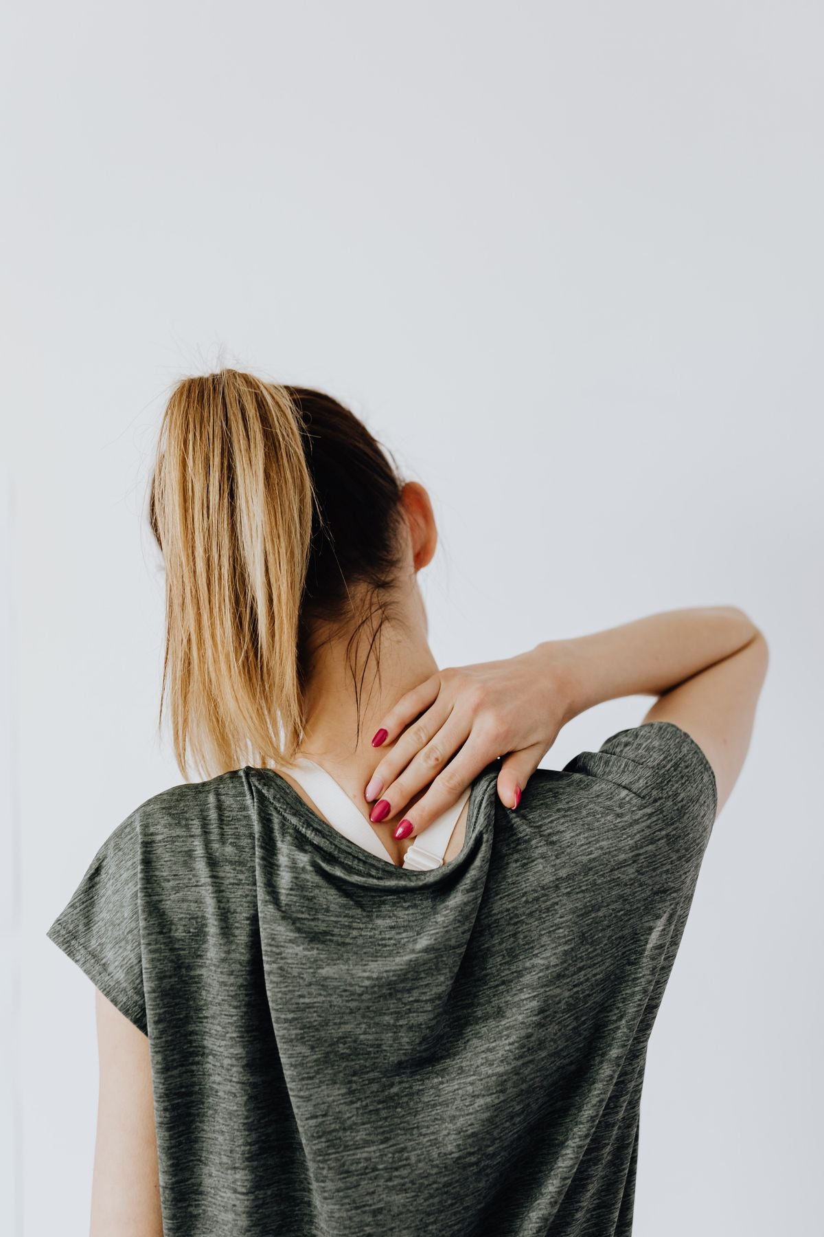 A woman holding the back of her neck, showing stiffness and discomfort