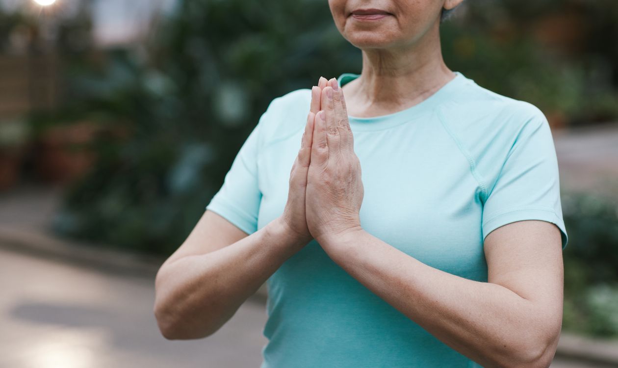 Senior woman in a peaceful outdoor yoga pose, gently stretching
