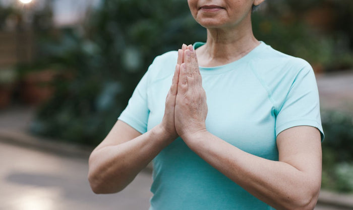 Senior woman in a peaceful outdoor yoga pose, gently stretching