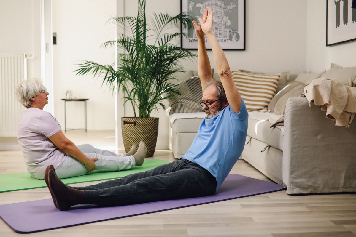 Elderly couple stretching gently together at home