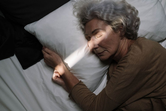 A senior woman sleeping peacefully in bed with soft lighting